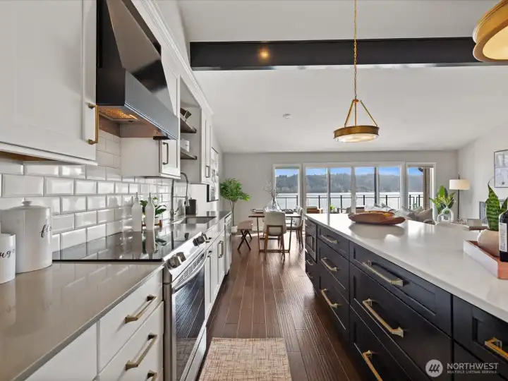 Kitchen with quartz countertops, tile backsplash, stainless steel appliances, and open layout to living area with Lake Sammamish views