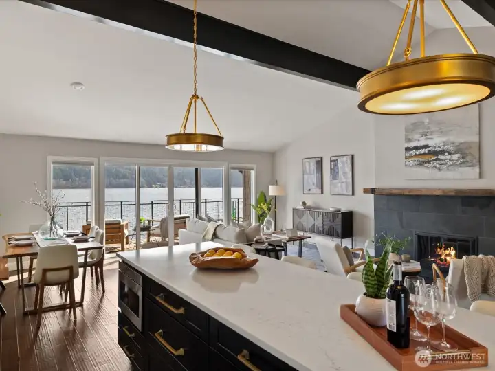 Open-concept kitchen, dining, and living area with island seating, hardwood flooring, and large windows overlooking Lake Sammamish