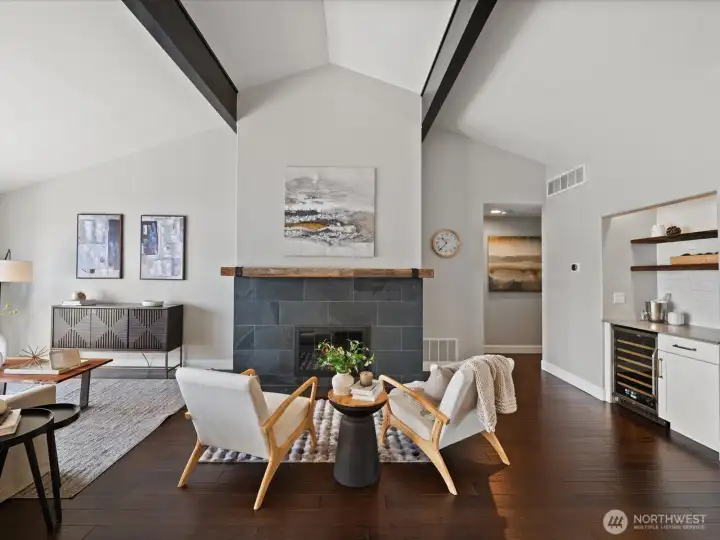 Living area with fireplace, vaulted ceilings, hardwood flooring, and open layout connecting to kitchen and dining space
