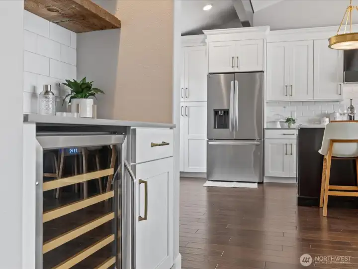 Kitchen detail with stainless steel refrigerator, hardwood flooring, and adjacent built-in beverage station
