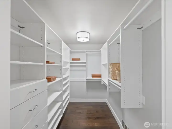 Walk-in closet with built-in shelving, drawers, and hardwood flooring