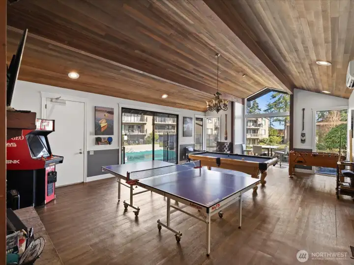 Community recreation room with game tables, seating area, and wood ceiling