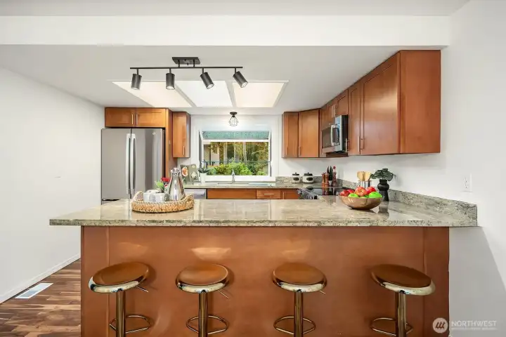 A generous breakfast bar with granite countertops and comfortable bar seating creates a casual and convenient space for everyday meals or entertaining guests. The open sight lines into the kitchen and beyond reflect the home's bright, connected layout that flows effortlessly from space to space.