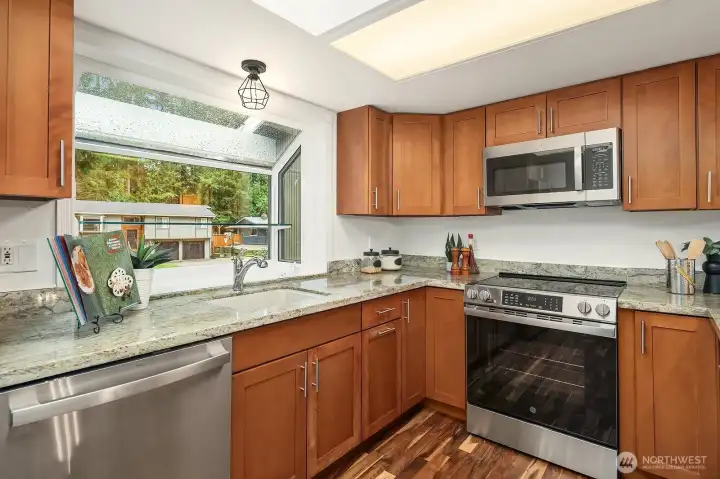 This well-appointed kitchen offers a smart and efficient layout with rich wood cabinetry, granite countertops, and a full suite of stainless steel appliances including a gas range and built-in microwave. A bright window above the sink brings in natural light and a pleasant view, making everyday tasks in this beautifully updated kitchen an absolute pleasure.