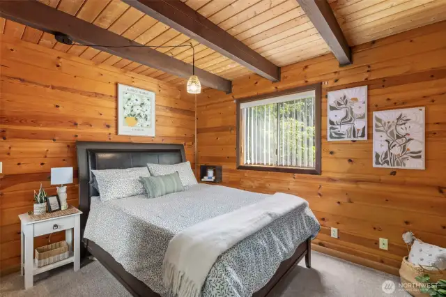 One of two main level bedrooms with beamed ceilings and large window.