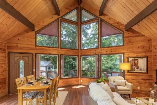 The great room features soaring beamed ceilings and a wall of windows looking out at your own personal forest.