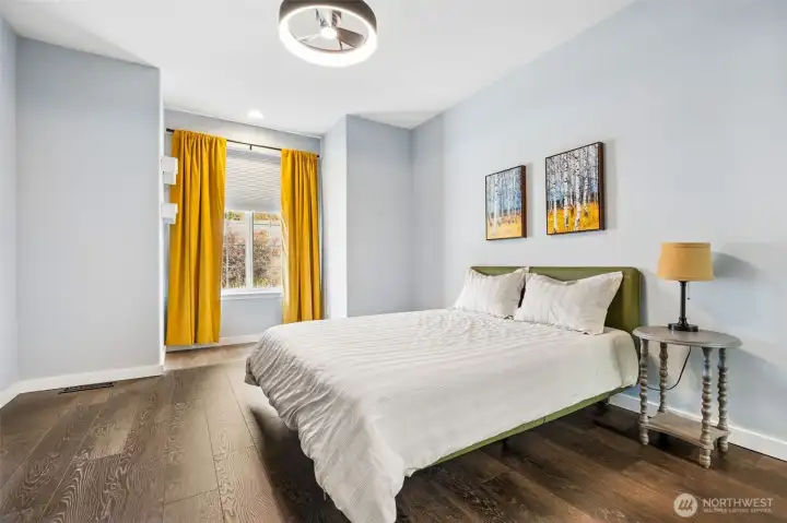 The primary suite sits right off the entry, giving it a level of separation that feels intentional. Guests head one way, you disappear into your own retreat. It’s private without being tucked away at the end of a maze. Inside, the scale delivers. Plenty of room for larger furniture without crowding the space, plus a dedicated reading nook by the window that feels like it belongs there. The ceiling fan with integrated LED lighting keeps the room comfortable and bright without cluttering the ceiling line.