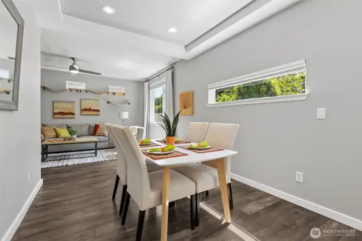A large picture window brings in natural light, while those upper transom-style windows along the wall solve the usual layout problem, light pours in, privacy stays intact, and your furniture goes wherever you want it. Hardwood floors run through with that same warm, multi-tone grain, paired with a soft silver-gray wall color and crisp white trim that keeps everything sharp. A modern ceiling fan anchors the space overhead, and at roughly 12 by 16 the living room, next to this Dining Room, has real room to spread out. A large picture window brings in natural light, while those upper transom-style windows along the wall solve the usual layout problem, light pours in, privacy stays intact, and your furniture goes wherever you want it. Hardwood floors run through with that same warm, multi-tone grain, paired with a soft silver-gray wall color and crisp white trim that keeps everything sharp. A modern ceiling fan anchors the space overhead, and at roughly 12 by 16 the living room, next to this Dining Room, has real room to spread out.