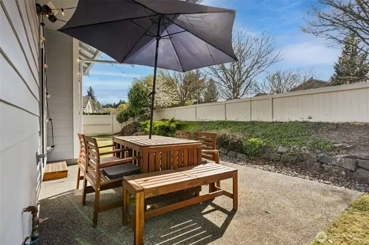 This patio is set up for easy outdoor living, right off the kitchen so everything flows without effort. There’s plenty of room to bring in seating, a table, maybe a grill moment that turns into a full evening, because this space invites it. The yard is fully fenced, giving you that sense of privacy and definition, while the surrounding trees along the sidewalk behind the home bring in a natural backdrop that shifts with the seasons. Lush green in the warmer months, rich color when fall rolls in, it’s a view that keeps evolving.