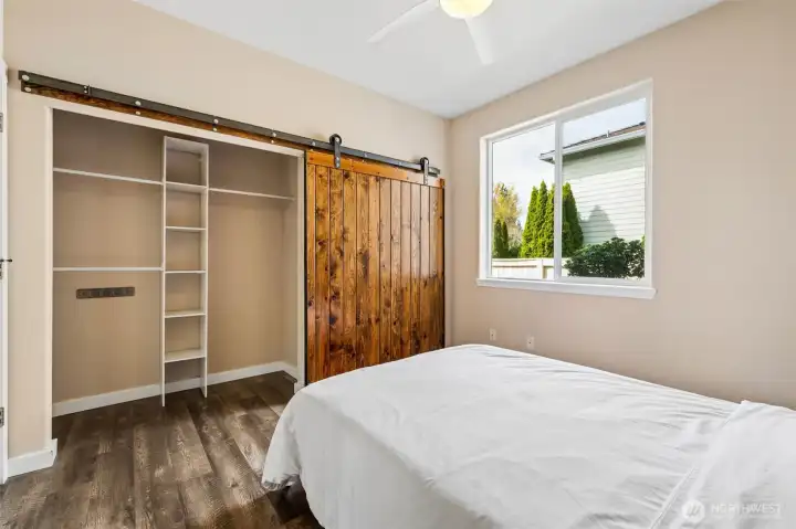 Tucked on the opposite side of the home from the primary suite, this split layout gives everyone their own space to breathe, no shared walls, no overlap, just a little extra peace built right in. The soft buff-toned walls keep things warm and easy, while the barn-style closet door brings in that rich wood texture that adds instant character. Inside, built-ins are already handling the organization, so nothing feels crammed or chaotic. And with a ceiling fan overhead, you’ve got your own comfort dialed exactly how you like it, whether that’s a cool night’s sleep or just a little white noise to round it out.