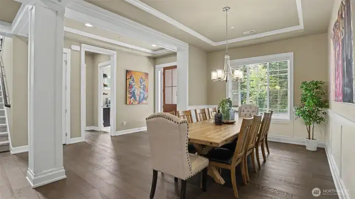 The dining room is highlighted by a coffered ceiling with crown molding detail and wide plank hardwood floors. Enjoy a peak into the den. The dining room is highlighted by a coffered ceiling with crown molding detail and wide plank hardwood floors. Enjoy a peak into the den.