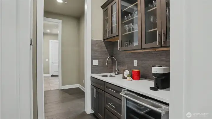 Convenient butler's pantry features glass inset cabinets, tiled backsplash, quartz counter, prep sink and wine cooler. Convenient butler's pantry features glass inset cabinets, tiled backsplash, quartz counter, prep sink and wine cooler.
