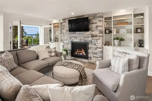 A gas fireplace, custom built-ins, and quartz cabinet tops with french doors leading to the deck.