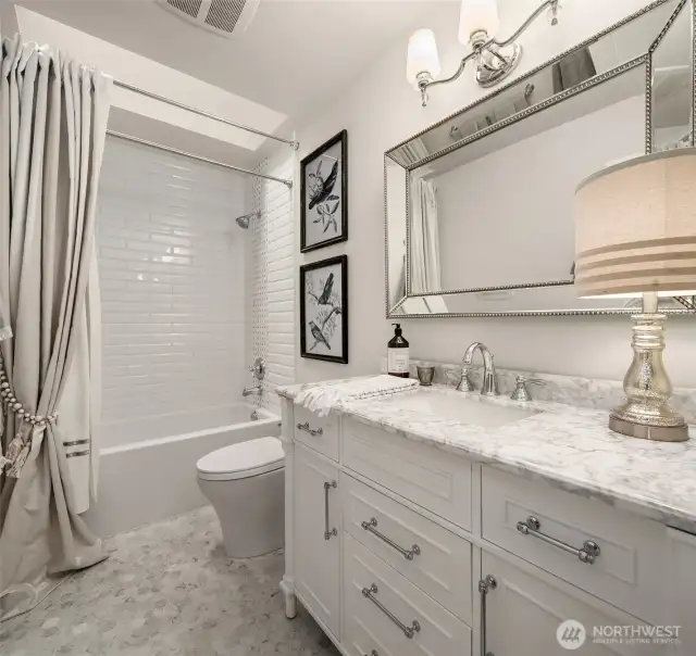 Guest bathroom with marble floors and marble vanity countertop.