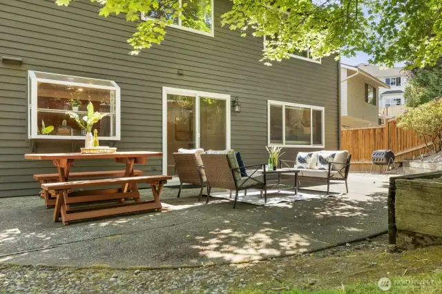 Outside, a patio sits under dappled shade and overlooks the spacious, fully fenced yard.