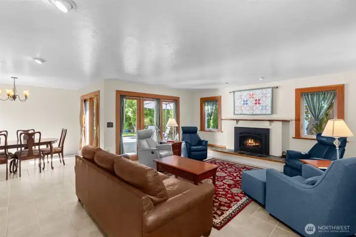 A wider view shows the dining room, revealing more windows/doors.  Don't miss the live edge mantel gracing the gas fireplace, and the slate hearth extending along the far wall.