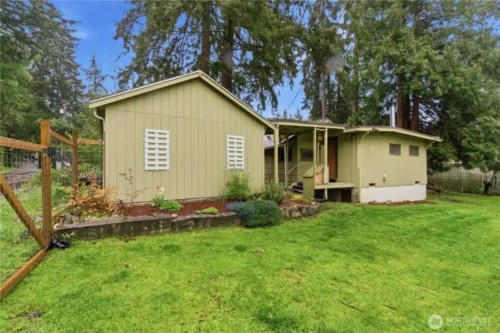 This view from the garden showcases the back of the home, highlighting its simple charm and the easy connection between the outdoor space and the interior.