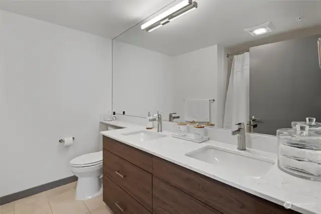 Primary full bath features double vanity and custom tile surround .