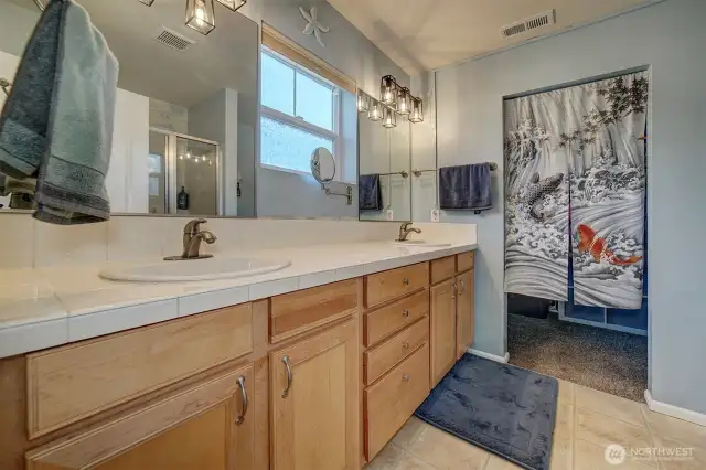 Primary bathroom with double vanities leads to walk-in closet