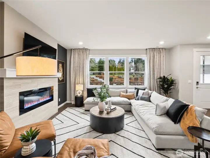 Large family room view with cozy fireplace with loads of windows. Photo is representational. Actual home is under construction and finishes and paint colors may vary. See site agent for details....