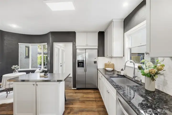 The kitchen with a view of the breakfast nook and the hallway leading to the primary suite.