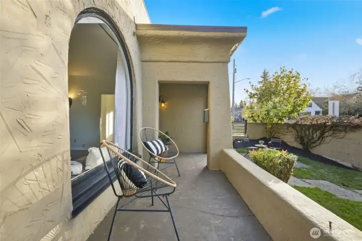 The front of the home features a wrap around porch framed by a stucco wall.