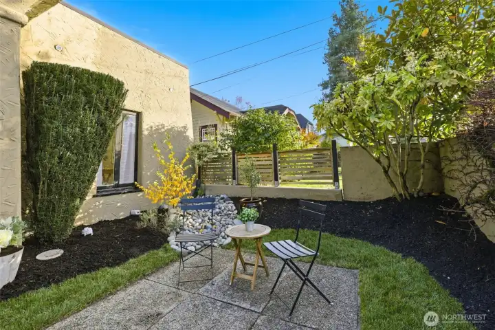 the aggregate concrete patio in front of the home is another place to retreat for quiet enjoyment. Here you can see the newly landscaped yard has fresh equity bark and a new rock covered drain.