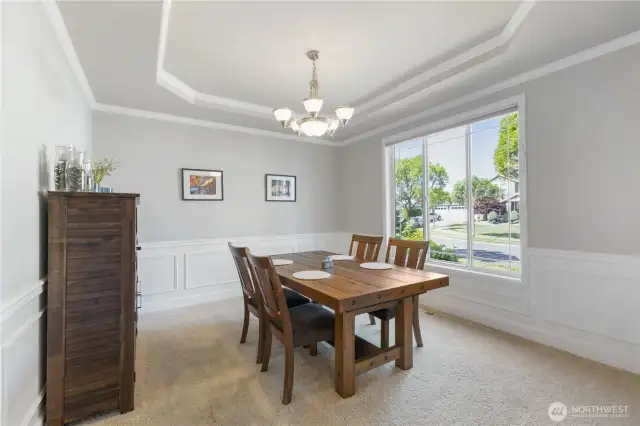 Elegant dining room with classic wainscoting and crisp white trim, enhanced by a large window that fills the space with natural light. A coved ceiling adds architectural charm, while convenient access to the butler’s pantry and kitchen makes entertaining a breeze.