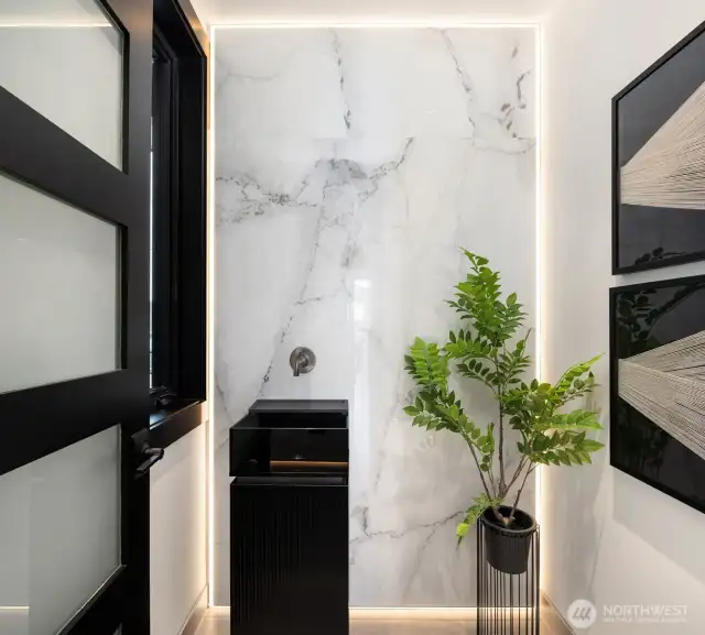 The powder room features a backlit marble slab that beautifully showcases the Italian glass pedestal sink—so chic!