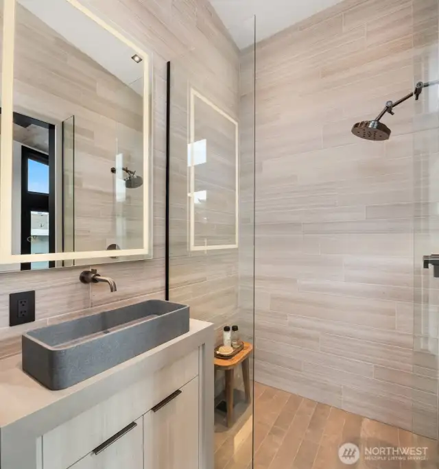 This bedroom offers its own floor to ceiling tiled bath with custom cabinetry and concrete surround pedestal.