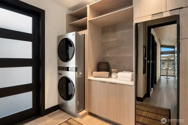 The utility room is surprisingly stylish, featuring a state-of-the-art wardrobe steamer and stunning floor-to-ceiling shelving and cabinetry. Smartly located under the breezeway and just across from the garage, it offers both function and flair the moment you come inside.