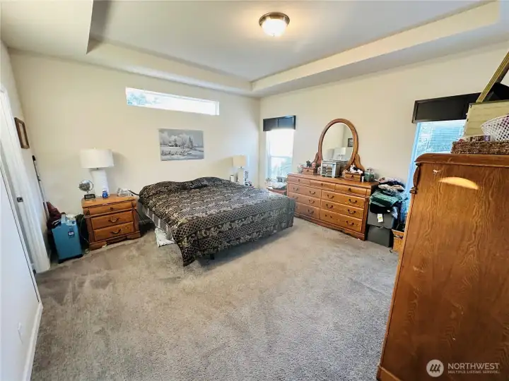 Large primary suite with cove ceiling and large windows, the light fixture is wired for easy installation of a fan. Large walk-in closet and custom bathroom.