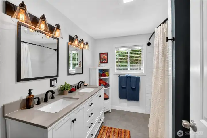 Main bath off hallway with double vanity and tub to the right.