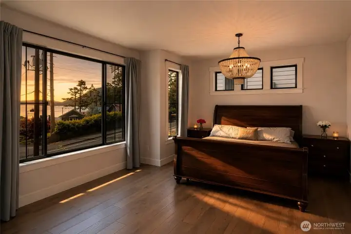 Spacious primary suite with sunset views and elegant chandelier lighting. Spacious primary suite with sunset views and elegant chandelier lighting.
