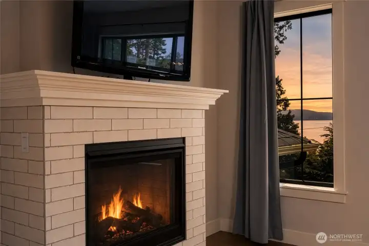 Primary bedroom retreat with cozy fireplace and serene sunset views. Primary bedroom retreat with cozy fireplace and serene sunset views.