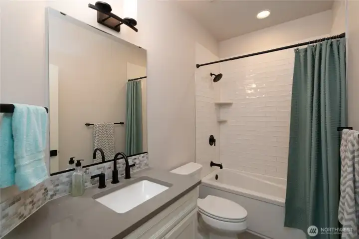 Modern full bath with sleek finishes and stylish black fixtures. Modern full bath with sleek finishes and stylish black fixtures.