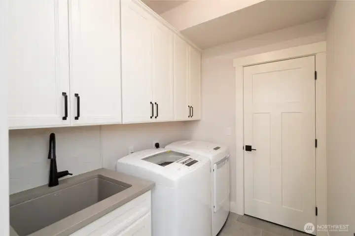 Functional laundry room with custom cabinetry and modern finishes. Functional laundry room with custom cabinetry and modern finishes.