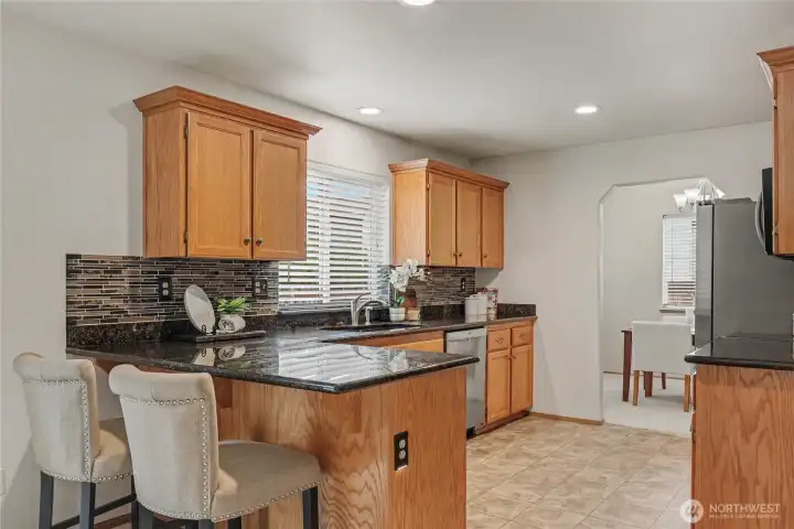 Kitchen with breakfast bar opens to family room and dining room.