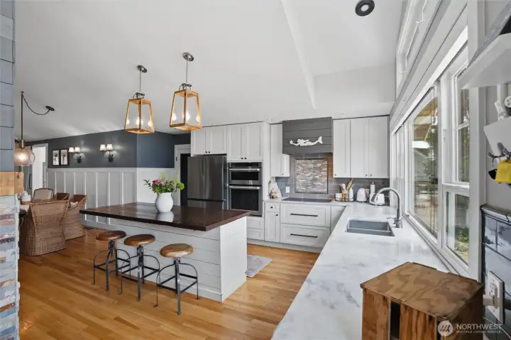 Gourmet kitchen featuring high-end appliances, custom soft-close cabinetry, and a spacious center island with breakfast bar seating. The chef-inspired workspace is highlighted by sleek, durable countertops, a modern undermount no-edge sink, and panoramic, uninterrupted views overlooking the vibrant activity of Horsehead Bay. Note: Refrigerator shown will be replaced with a different unit prior to closing. Gourmet kitchen featuring high-end appliances, custom soft-close cabinetry, and a spacious center island with breakfast bar seating. The chef-inspired workspace is highlighted by sleek, durable countertops, a modern undermount no-edge sink, and panoramic, uninterrupted views overlooking the vibrant activity of Horsehead Bay. Note: Refrigerator shown will be replaced with a different unit prior to closing.