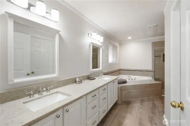 The luxurious primary ensuite features dual vanities, a spacious walk-in closet, a soaking tub, a glass-enclosed shower, and a private water closet.