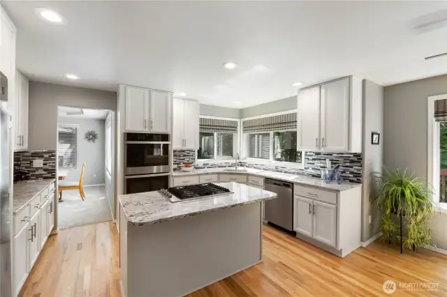 Blending function and elegance, the updated kitchen features beautiful hardwood floors, a cozy breakfast nook, and an island with an eat-up bar—perfect for casual dining and everyday living.