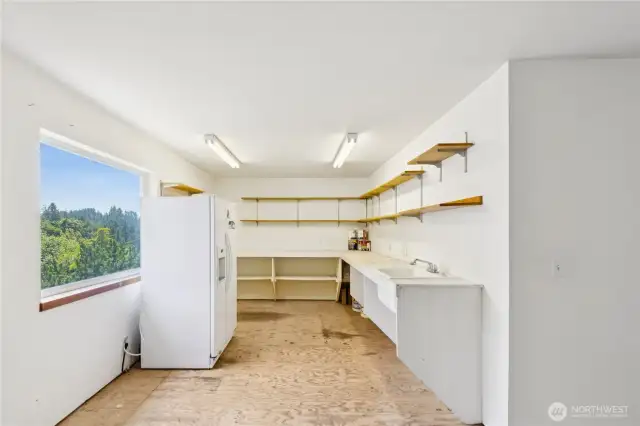 Shop with utility sink and garage fridge set off the garage bays.
