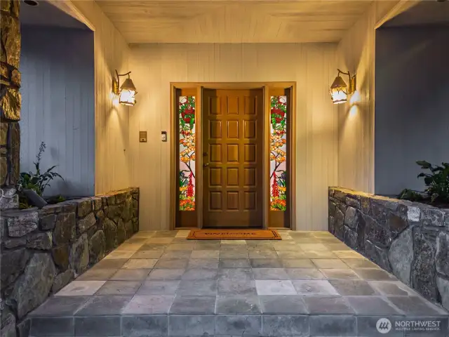 Large entry with stone planters and custom stained glass sidelights.