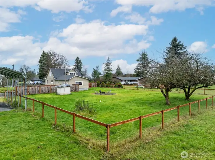 Back yard is fully fenced for your 2-legged and 4-legged friends. Little building in the yard is the well-house. RV carport at left of photo.