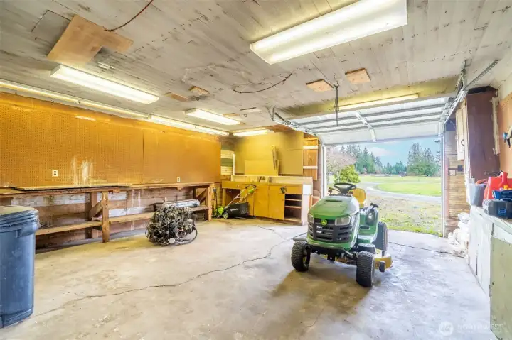 One end of the shop includes a roll-up garage door and concrete flooring for yard equipment.