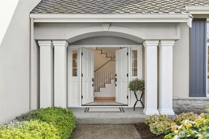 A stately and modern covered entry with double doors and gleaming hardwood floors...