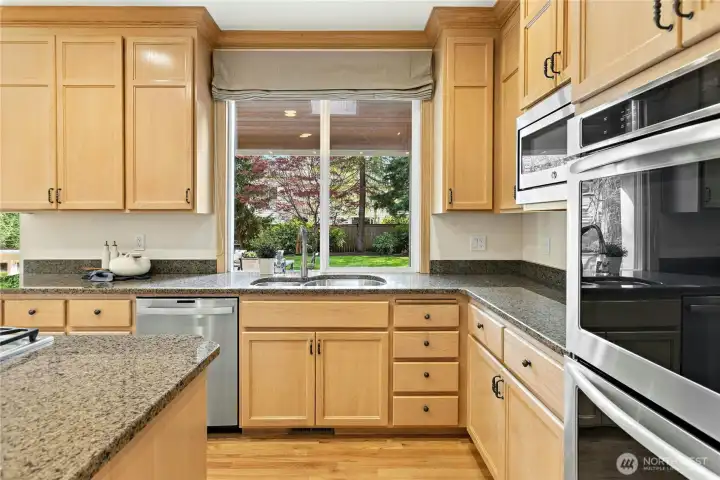 Granite counters and stainless appliances shine. Sparkling views through to the back yard can be enjoyed from here. Note the covered patio with skylight out this window which allows for a beautiful connection to outdoor living plus allows lots of light to shine in!