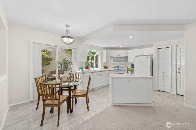 The kitchen features an everyday eating area, a garden window, and ample counter and cabinet space, including an island and pantry. The door on the right leads to the garage.