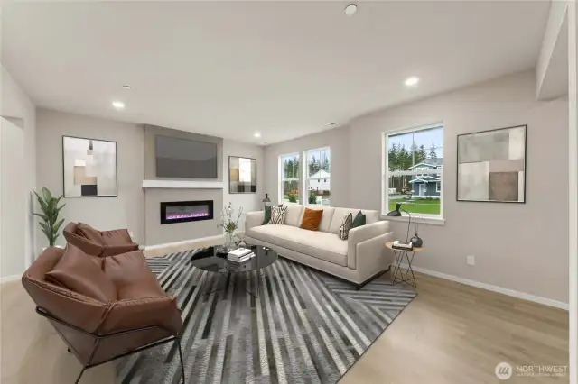Family room with cozy fireplace with lots of windows to let natural light in.  Actual home is under construction and materials, colors, and finishes will vary. See site agent for details.