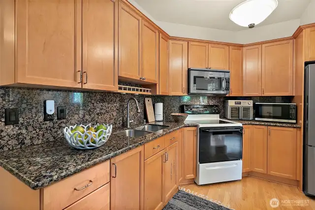 Well-appointed downstairs kitchen featuring granite counters, matching granite backsplash. Full size refrigerator, stove, microwave and abundant storage.  This kitchen offers plenty of counter and cabinet space.